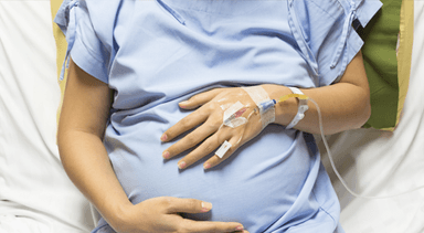 woman in hospital holding pregnant belly