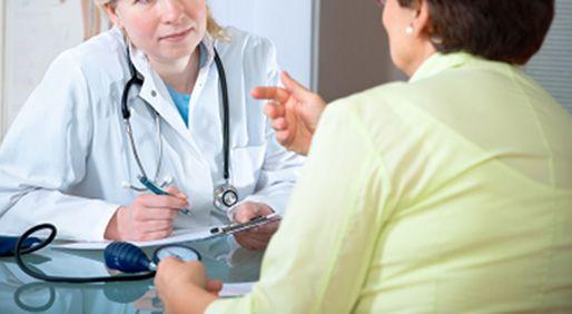 female clinician in a white coat listens to a patient