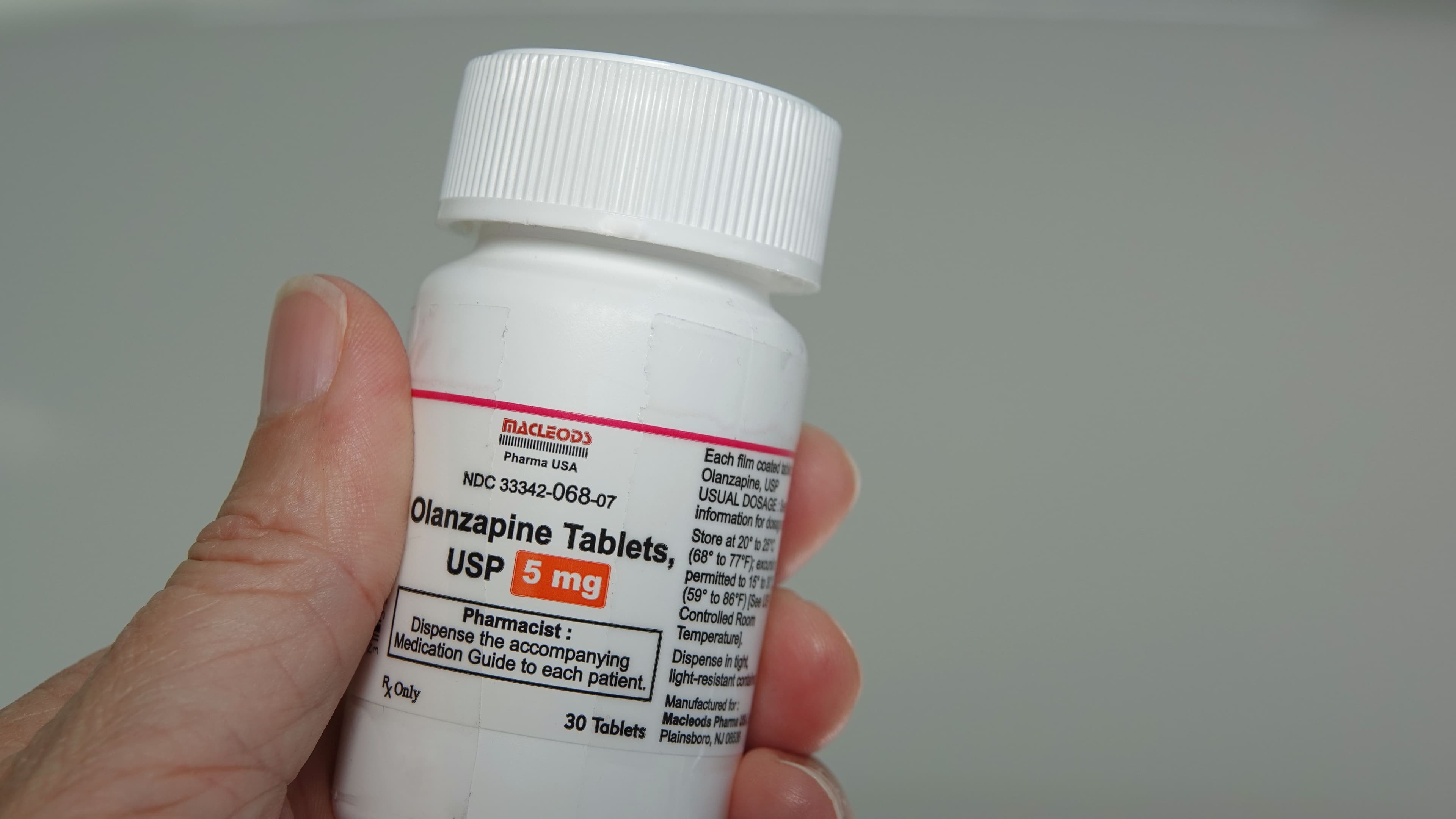 Hand holding a container of Olanzapine, an atypical antipsychotic medication used to treat schizophrenia and bipolar disorder. Illustrative editorial taken in Vista, CA / USA on July 7, 2020